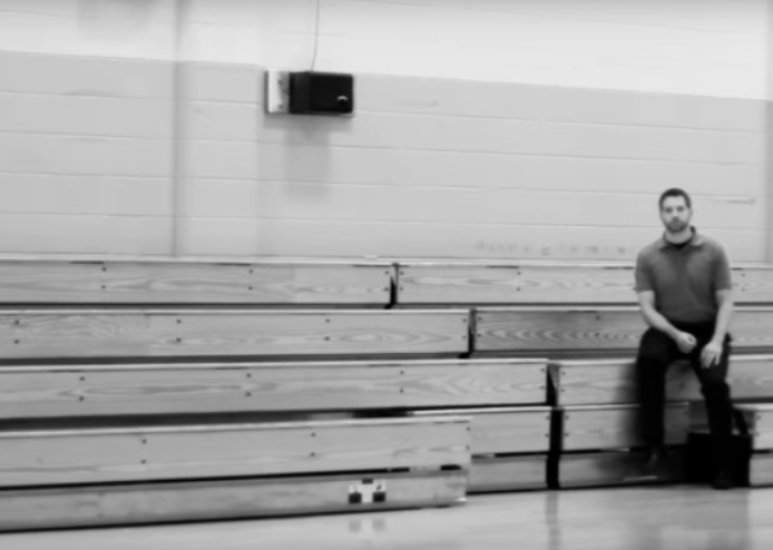Teacher sitting in the bleachers of a gym