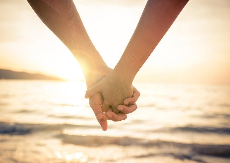 Couple holding hands at sunset