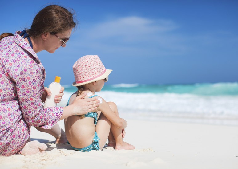 Mom applying sunscreen to child at beach