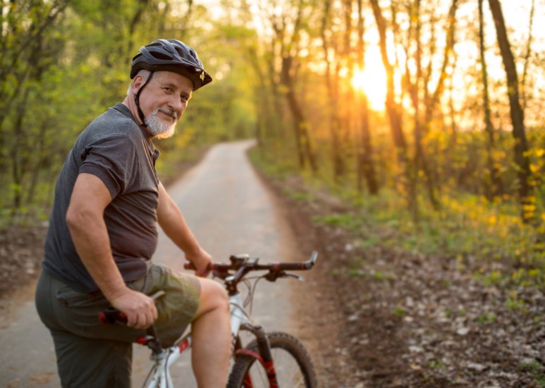 Middle-aged man biking on a trail