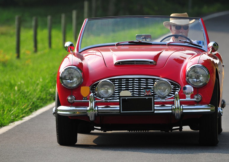Older man driving red convertible