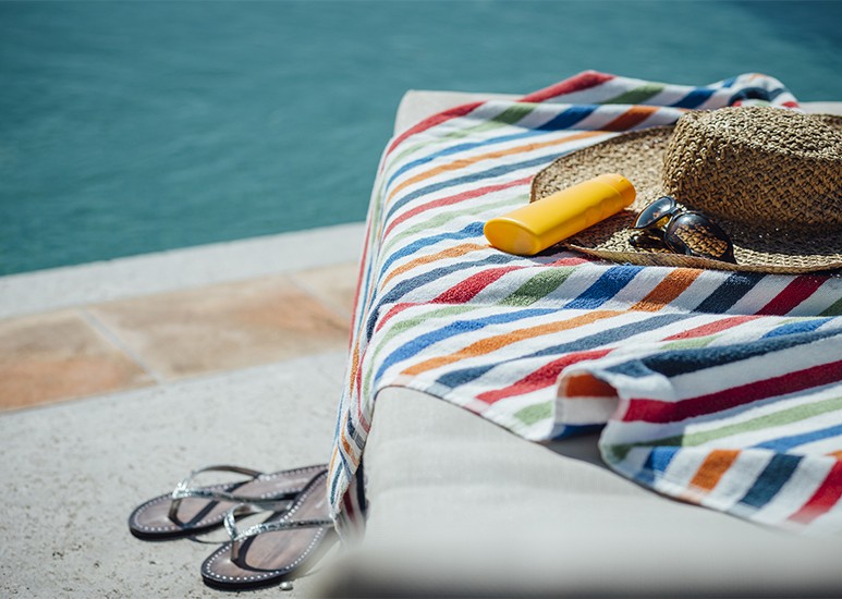 Lounge chair with towel and sunblock by pool