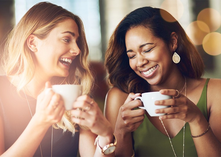 Two female friends laughing over coffee