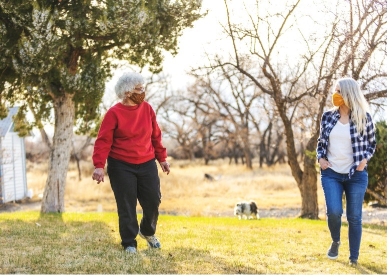 two women walking outside with masks on