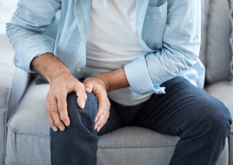 man on couch with knee pain