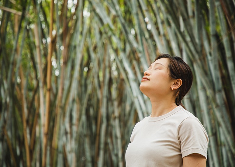 Peaceful, healthy woman by bamboo