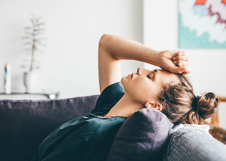 Woman laying on a sofa feeling sad 