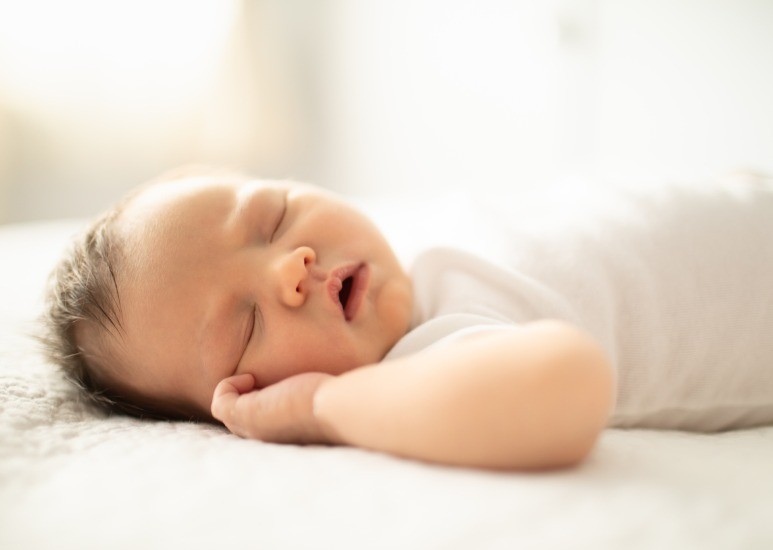 sleeping newborn on flat fitted bedsheet 