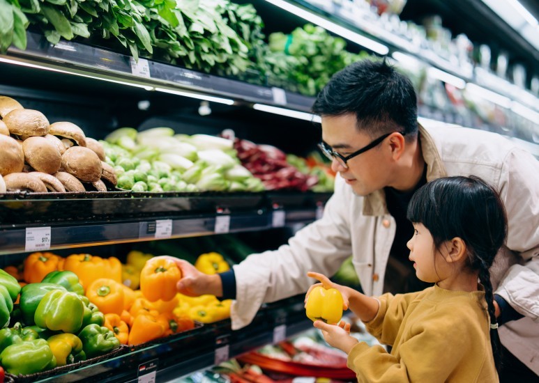 Dad and daughter selecting fresh vegetables at the grocery store