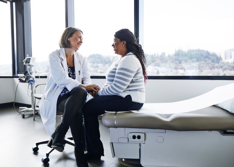 Female healthcare provider visiting with a female patient in an exam room