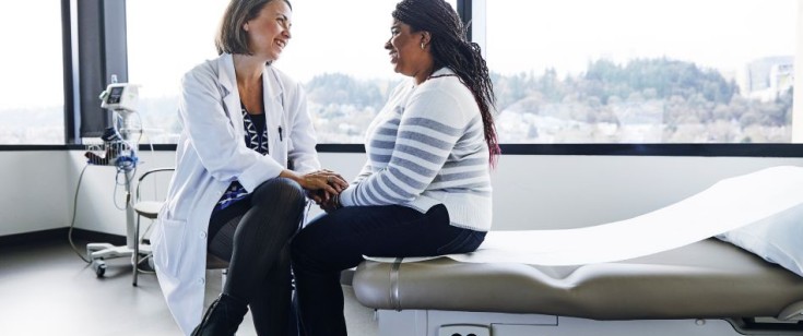 Female healthcare provider visiting with a female patient in an exam room