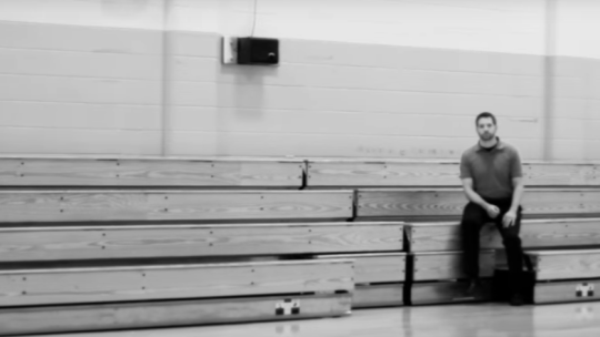 Teacher sitting in the bleachers of a gym