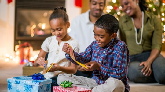 Kids opening Christmas gifts with family