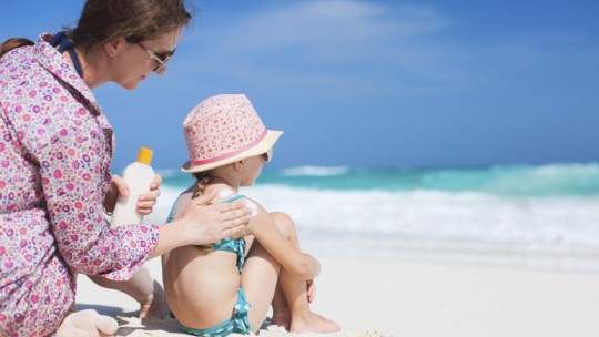 Mom applying sunscreen to child at beach