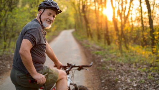 Middle-aged man biking on a trail