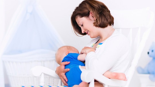 Mother breastfeeding and rocking baby