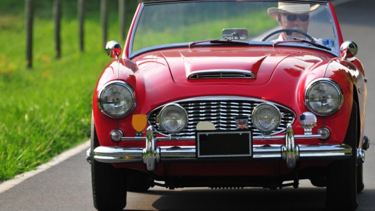 Older man driving red convertible