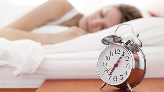 Woman sleeping with alarm clock on nightstand