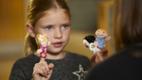 Child and therapist doing play therapy with finger puppets