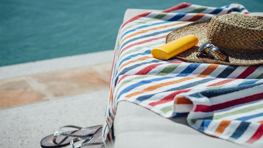 Lounge chair with towel and sunblock by pool