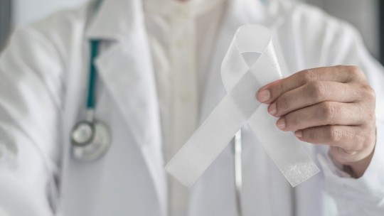 Doctor holding ribbon for lung cancer awareness