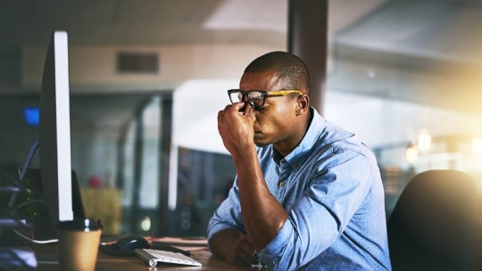 man tired at work computer desk