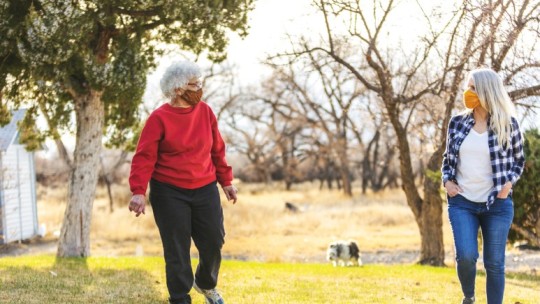 two women walking outside with masks on