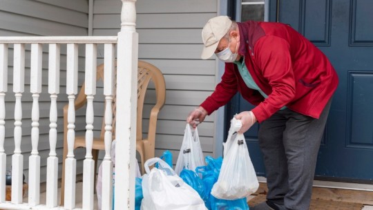 man putting groceries on porch for elderly