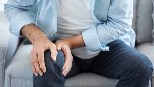 man on couch with knee pain
