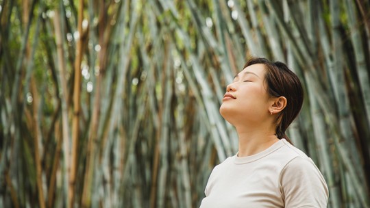 Peaceful, healthy woman by bamboo