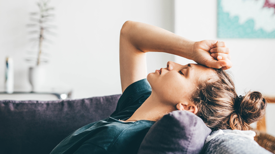 Woman laying on a sofa feeling sad 