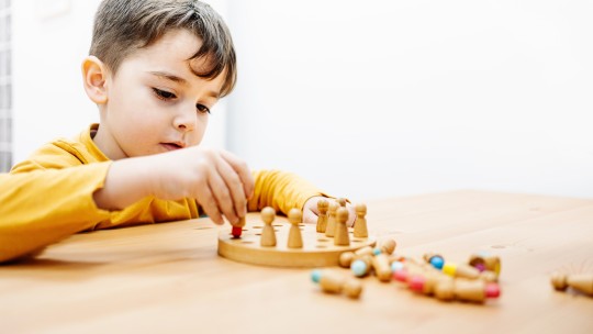 Young child engaged in quiet play with a board game.