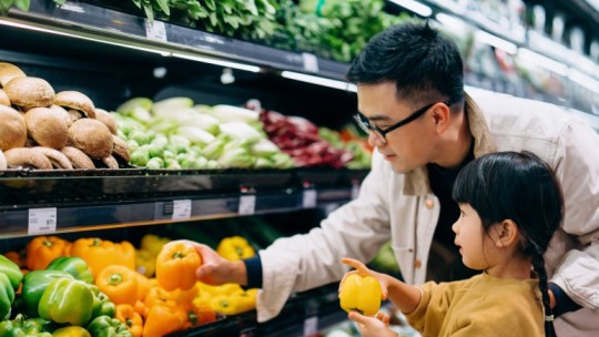 Dad and daughter selecting fresh vegetables at the grocery store