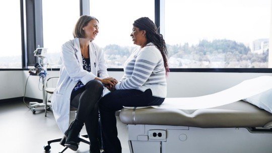 Female healthcare provider visiting with a female patient in an exam room