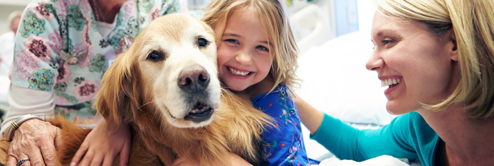 Pediatric girl patient with therapy dog, mom and nurse