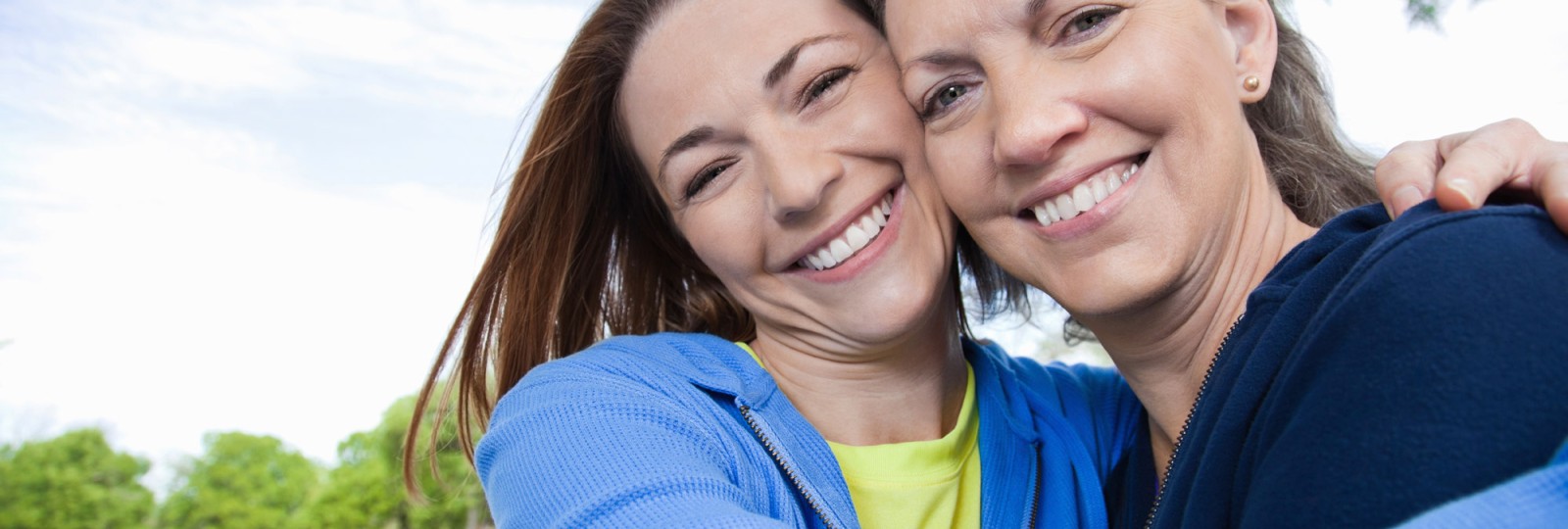 Mom and daughter hugging and smiling outside