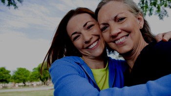 Mom and daughter hugging and smiling outside