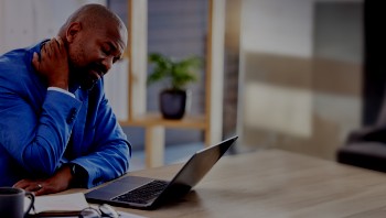 Person with neck pain working on a laptop