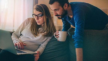 Pregnant couple looking at laptop