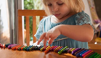 Little girl playing with multi-colored crayons