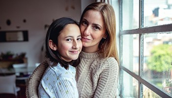 Mom and daughter hugging by a window