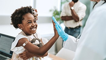 Doctor high-fiving with a pediatric patient after a vaccine